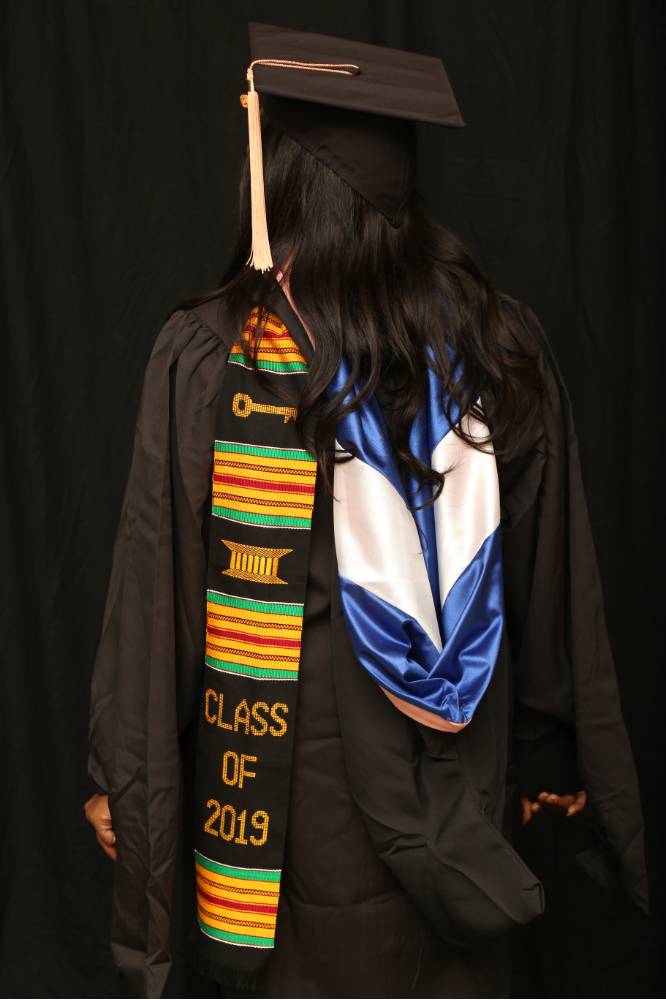 woman shows off her cap and gown for a picture